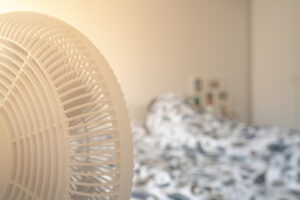 Person schläft an Sommertag im Bed mit laufendem Ventilator
