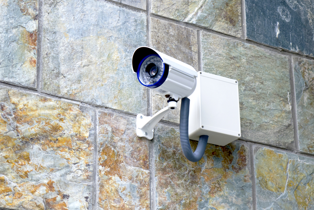 Überwachungskamera an Fliesen einer Hauswand