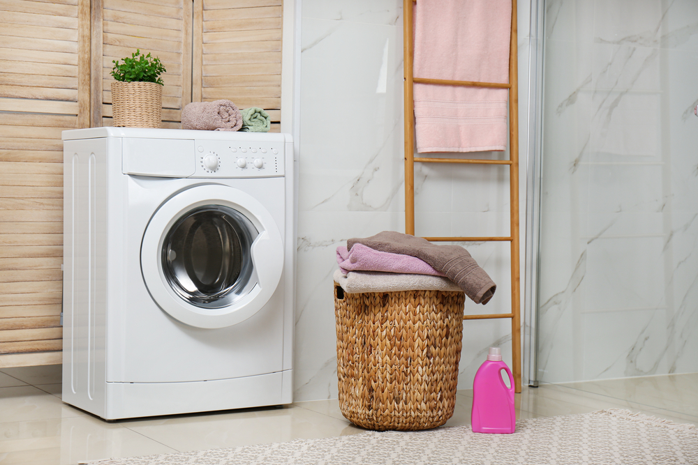 Moderne Waschmaschine sowie Wäsche in einem Korb in einem Badezimmer