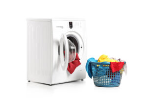Mit Dreckwäsche gefüllte Waschmaschine und daneben ein gefüllter Wäschekorb vor weißem Hintergrund