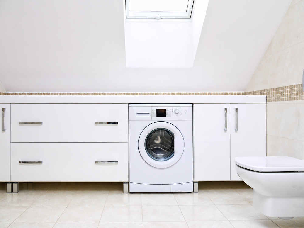 Modernes Badezimmer mit weißen Schränken und einer Waschmaschine