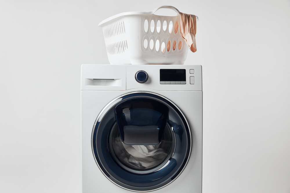 Waschmaschine mit weißem Wäschekorb obendrauf