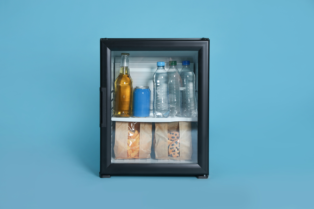 Mini-Kühlschrank gefüllt mit Getränken vor türkisfarbenem Hintergrund