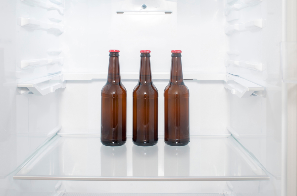Drei braune Glasflaschen in einem sonst leeren Kühlschrank