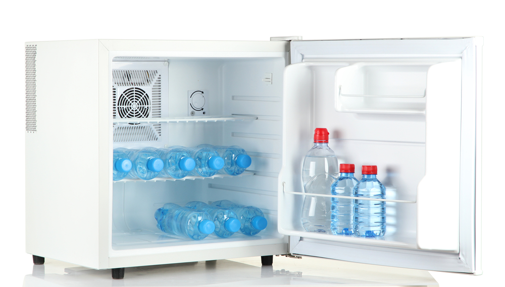 Geöffneter Mini-Kühlschrank vor weißem Hintergrund, der mit Wasserflaschen gefüllt ist
