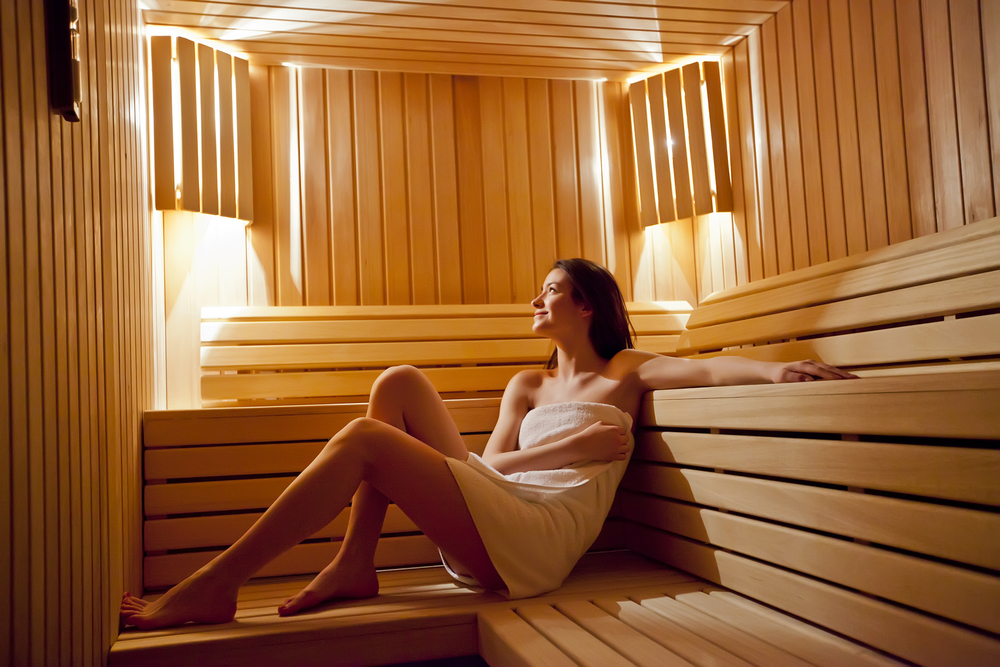 Junge Frau in weißes Handtuch gehüllt in einer Sauna