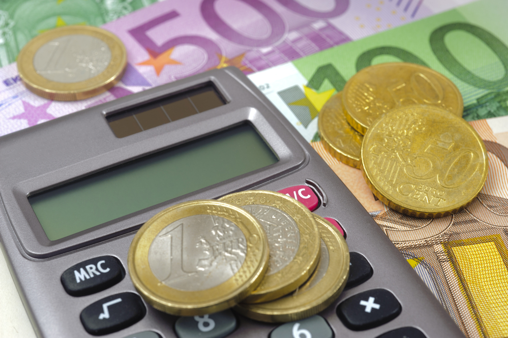 Euro Münzen auf einem Taschenrechner, daneben Euro Scheine