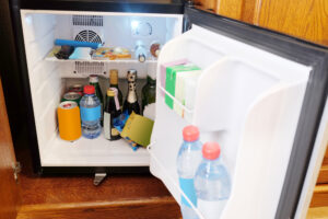 Geöffneter Minikühlschrank, der mit Getränken und Lebensmitteln gefüllt ist