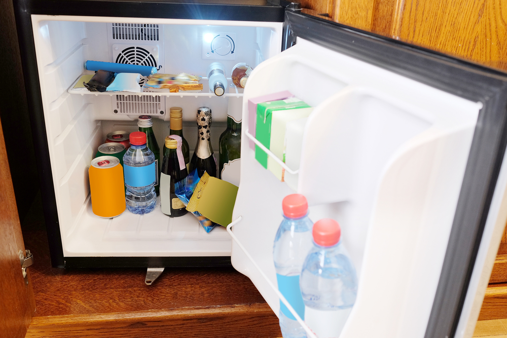 Geöffneter Minikühlschrank, der mit Getränken und Lebensmitteln gefüllt ist