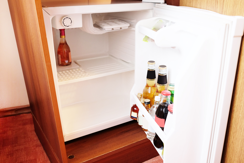 Geöffneter Mini-Kühlschrank, in dem ein paar kleine Getränkeflaschen stehen
