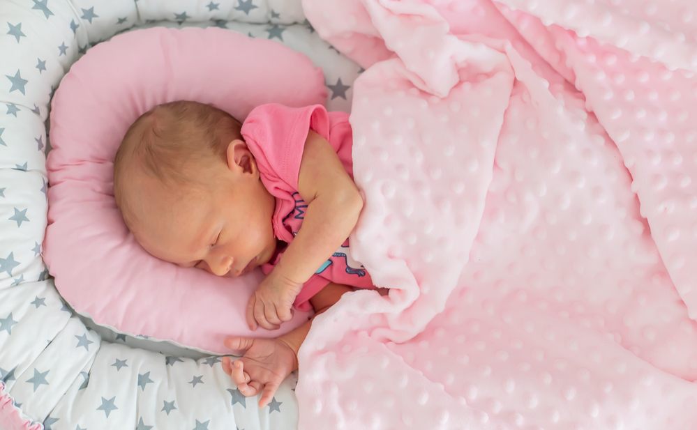 Neugeborenes, das im Babybett schläft